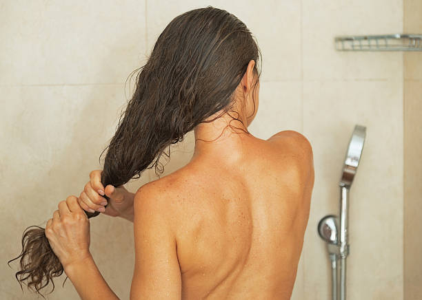 istock woman squeezing hair after shower 475212959