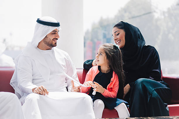 Traditional  Arabic family enjoying at lounge Traditional 3 generation middle eastern family wearing traditional arabic clothes (mother, father, grandfather and daughter) sitting, talking and having fun at lounge of shopping mall at sunny weekend day. Dubai, United Arab Emirates, UAE. emirati culture photos stock pictures, royalty-free photos & images