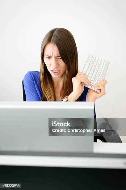 Angry Female Office Worker Attacks Computer Screen With Keyboard Stock Photo - Download Image Now