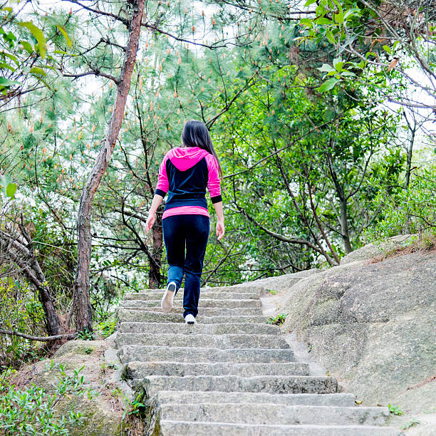 Asian woman climbing stairs outdoors.