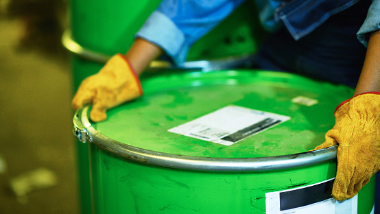 Human hands in protective gloves holding oil drum