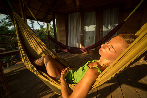 istock Young woman sleeping on hammock at sunset 475229166