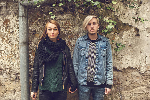 istock Young serious couple holding hands against the wall. 475229888