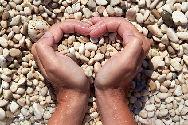 Hands in the form of heart with pebbles inside stock photo