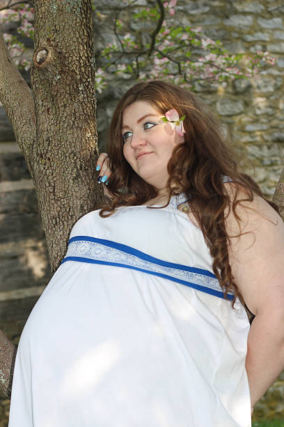 istock Pregnant Woman by Tree Poses For Camera 475234024