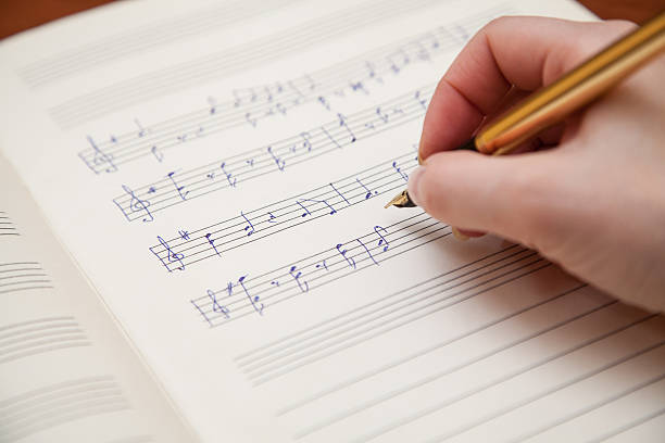 Hand with pen and music sheet Hand pointing with pen to music book with handwritten notes composer stock pictures, royalty-free photos & images