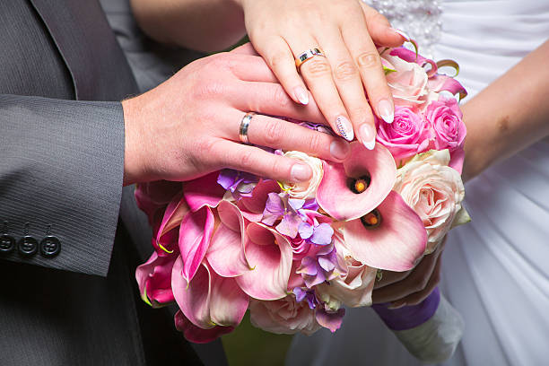 Hands of bride and groom holding wedding bouquet stock photo