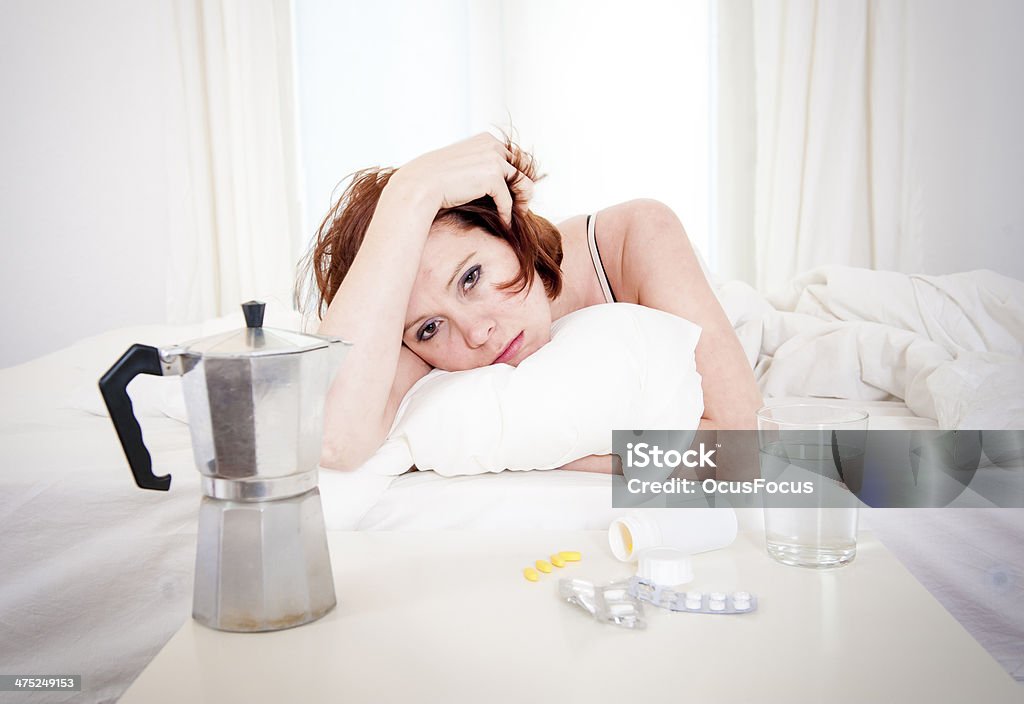 red haired girl with hangover wanting coffee in bed red hair girl hungover wanting coffee and medication to help with her hungover in bed Abuse Stock Photo