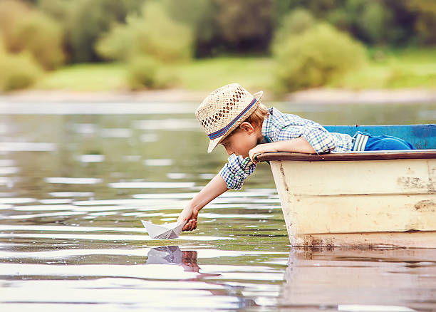 istock Little boy launch paper ship from boat 475251714