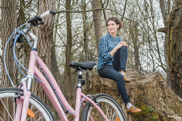 Brunette girl sitting on tree stump with hands on knee