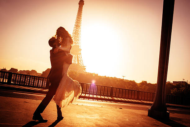 Parisian wedding Young married couple is kissing on Pont d'Lena while sun is rising. There is an Eiffel tower in the background.  paris france eiffel tower love kissing stock pictures, royalty-free photos & images