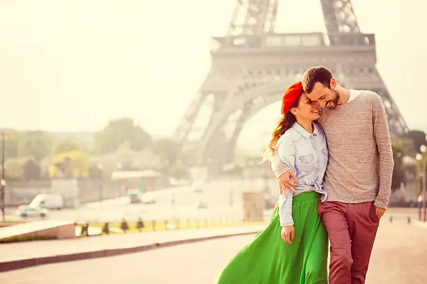 Young loving couple sharing their love and affection in front of the Eiffel tower in Paris, France. 