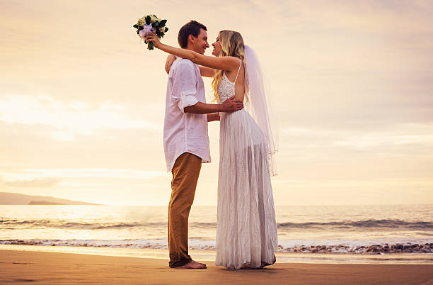istock bride and groom on beach at sunset 475253983