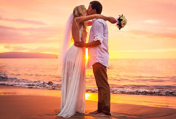 istock bride and groom on beach at sunset 475254453