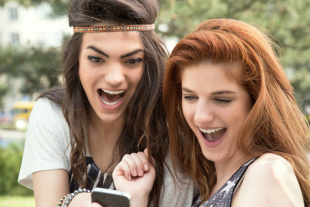 istock Smiling young girls reading message 475256750