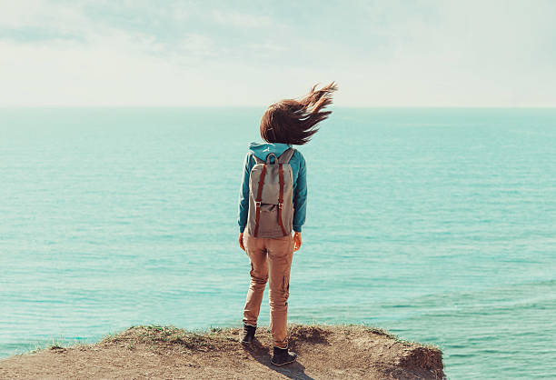 istock Woman standing on coastline in windy weather 475258266