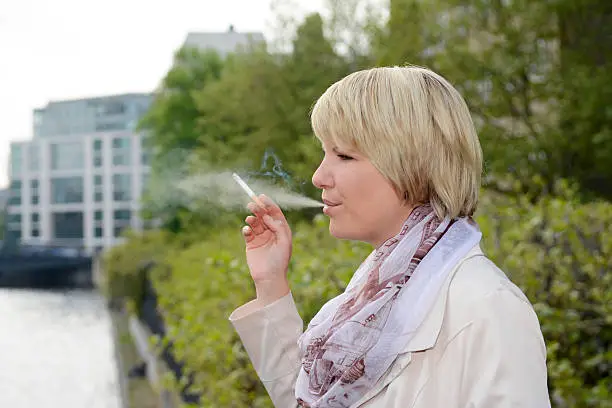 Photo of Blonde young woman smoking at Spree river, Berlin, Germany