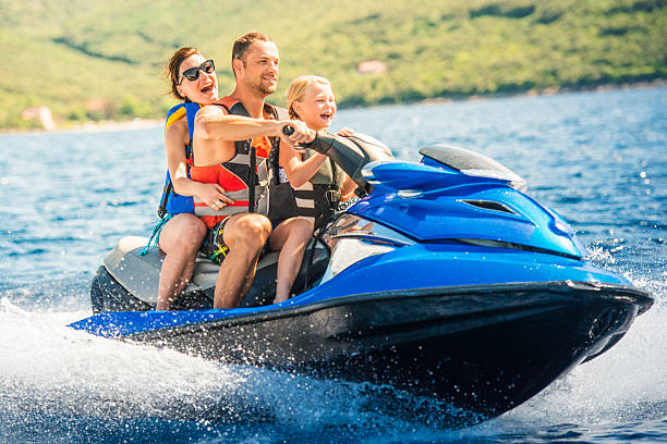 Family Riding a Jet Boat Family having fun riding a water scooter on the sea. motorized vehicle riding stock pictures, royalty-free photos & images