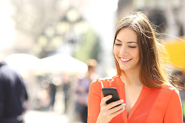 mulher vestindo camiseta laranja de mensagens de texto no telefone inteligente - video call imagens e fotografias de stock