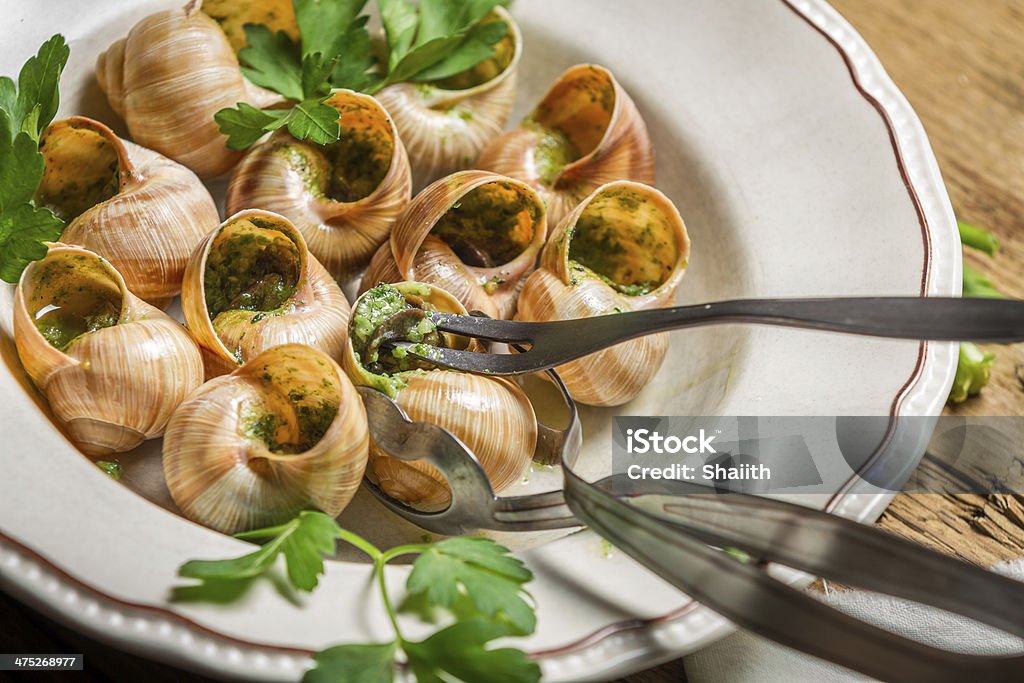 Closeup of eating the fried snails with garlic butter Closeup of eating the fried snails with garlic butter. Escargot Stock Photo