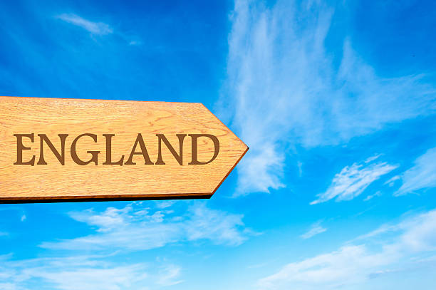 Wooden arrow sign pointing destination ENGLAND against clear blue sky with copy space available. Travel destination conceptual image