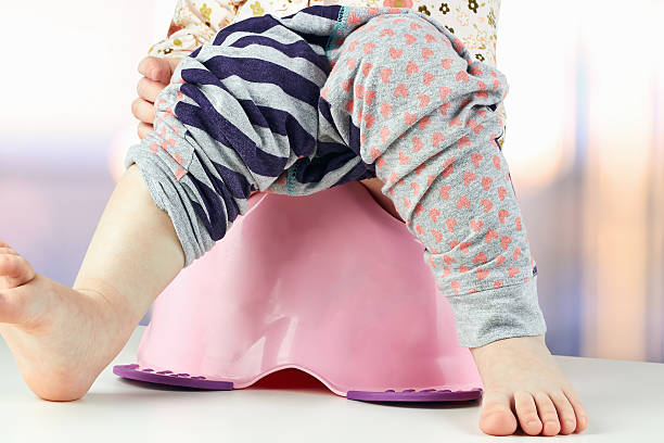 istock Children's legs hanging down from a chamber-pot on a green 475275890