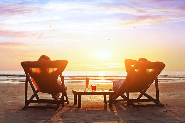 happy couple on the beach happy couple enjoy luxury sunset on the beach during summer vacations deck chair stock pictures, royalty-free photos & images