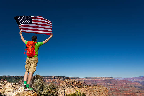 istock Man's back with rucksack, USA flag, Grand Canyon 475277432