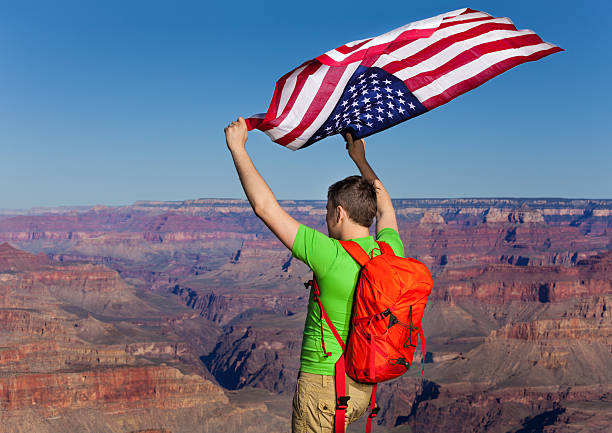 istock Back of a man with rucksack holding American flag 475280444