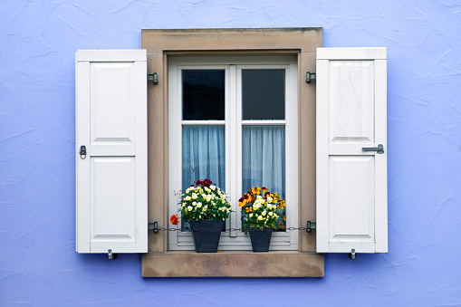 colorful window with shutters and two flower pots