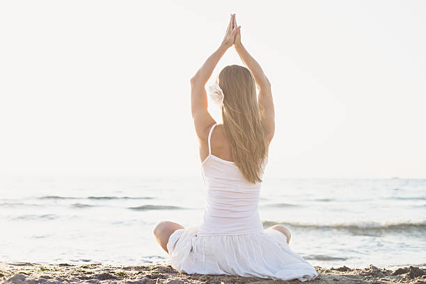 istock Young woman meditation on the beach 475283155
