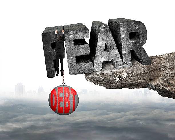 istock Man shackled debt ball hanging fear word edge cliff cloudscape 475285484
