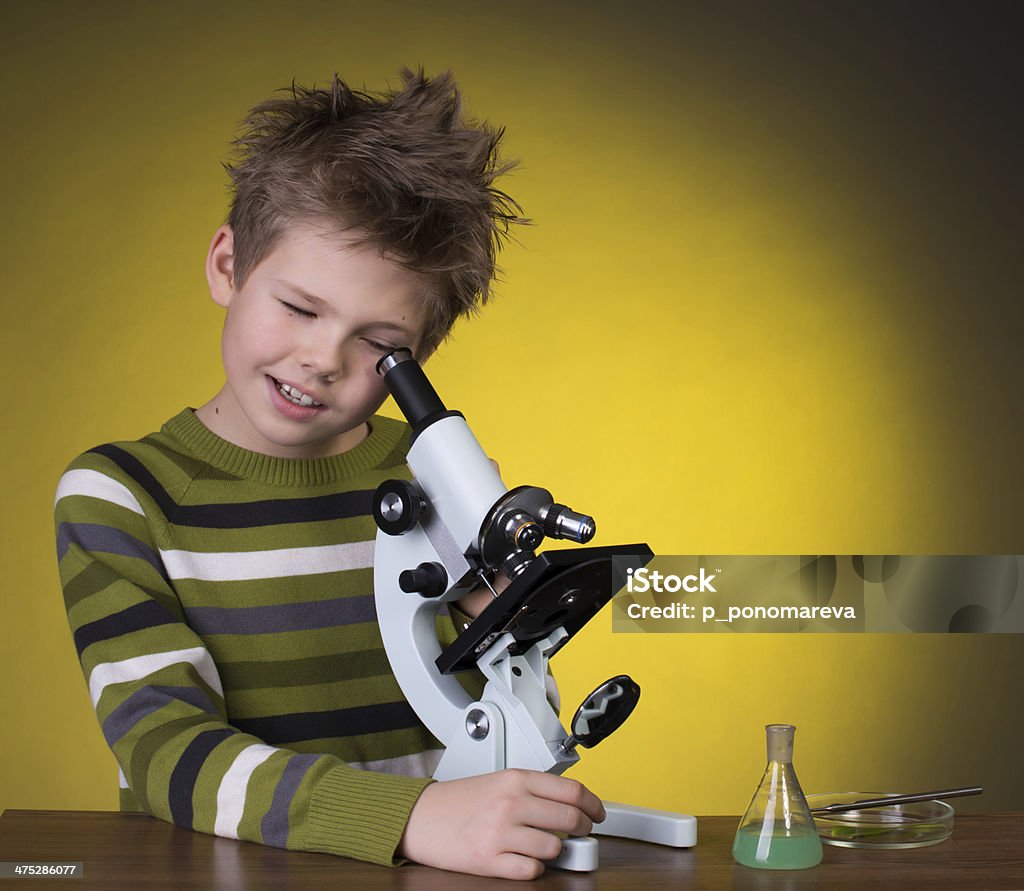 The boy with a microscope on a yellow background. Education. Little boy making science experiments. Child Stock Photo