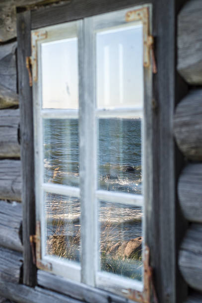 istock Seashore reflection in rustic cottage window of old wooden pisca 475291804