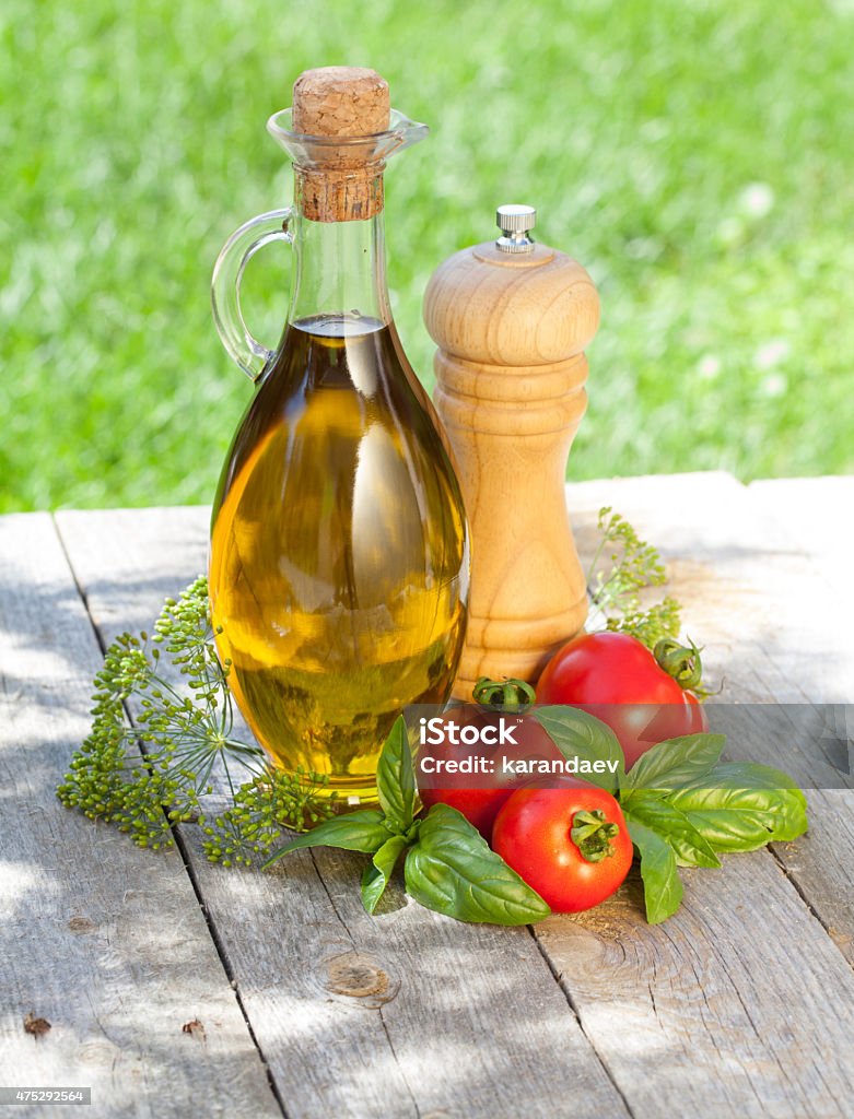 Olive oil bottle, pepper shaker, basil and ripe tomatoes Olive oil bottle, pepper shaker, basil and ripe tomatoes on wooden table 2015 Stock Photo