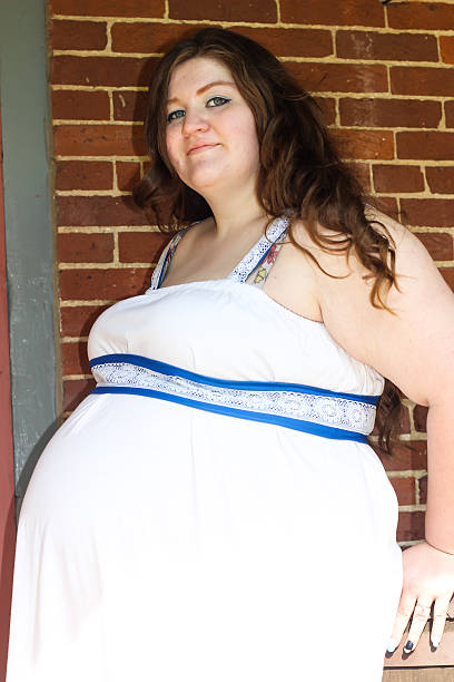 istock Pregnant Woman by Brick Wall Poses For Camera 475294706