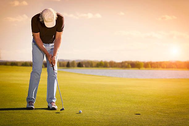 Senior golf player on green with copyspace. Male senior golf player putting on green at beautiful sunset, with empty copyspace. putting golf stock pictures, royalty-free photos & images