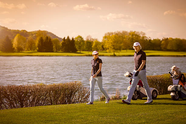 sênior casal andando no campo de golfe. - senior couple golf retirement action - fotografias e filmes do acervo