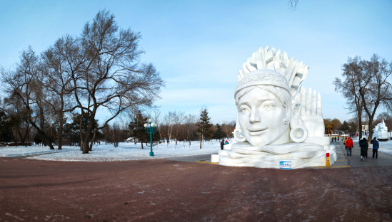 Harbin, China - January 9, 2014: Snow Girl sculpture. People are walking. Located in Sun Island Park of Harbin City, Heilongjiang Province, China.