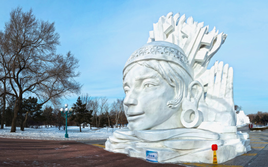 Harbin, China - January 9, 2014: Snow Girl sculpture. People are walking. Located in Sun Island Park of Harbin City, Heilongjiang Province, China.