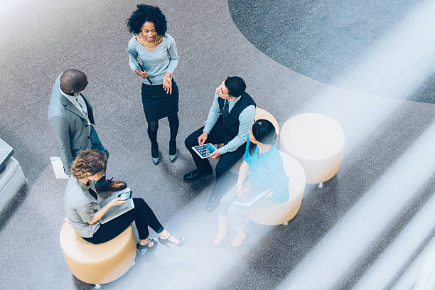 Overhead view of business people in a meeting Overhead view of multiracial business team having a meeting in the Office Lobby 21st century stock pictures, royalty-free photos & images