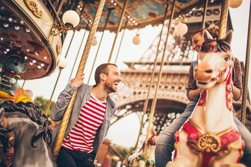 Photo of smiling loving couple at the carousel under the Eiffel Tower