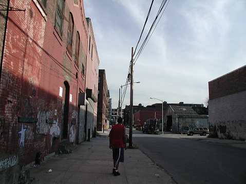 Brooklyn, NY, USA - September 6, 2003: View of man walking down West Street in Brooklyn. The old building on the left has since been replaced with a modern apartment building.