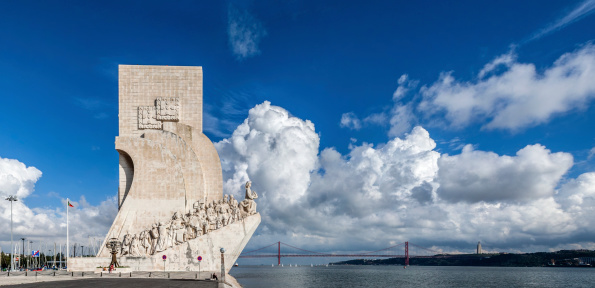 Lisbon, Portugal - November 5, 2013: Tourists stroll near the popular Padrao dos Descobrimentos (Sea Discoveries Monument) enjoying the view of the Tagus River and the 25 de Abril Bridge. Belem District of Lisbon, Portugal