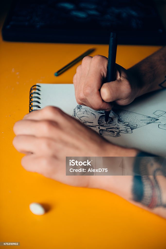 Tattoo Artist Drawing Young tattoo artist draw a new sketch on paper before tattooing on skin 20-24 Years Stock Photo