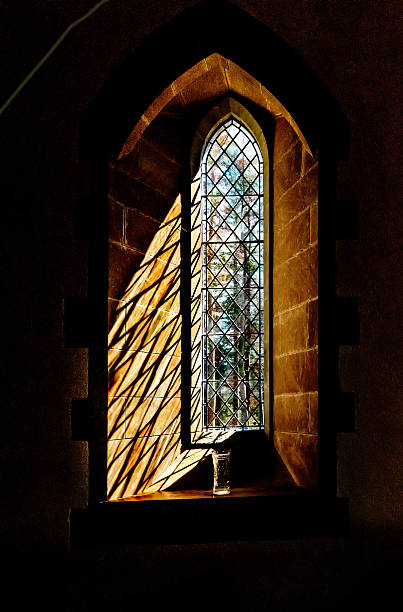 istock Sun lit arched leaded stain glass window with vase 475318280
