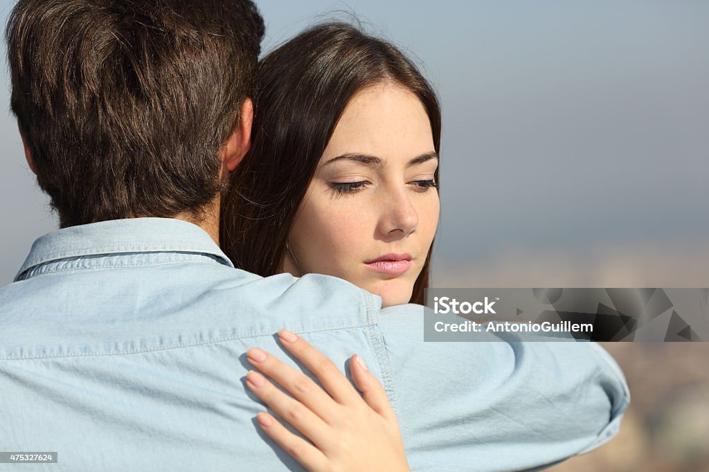 Sad woman hugging her boyfriend couple problems Sad woman hugging her boyfriend and looking down couple problems concept Infidelity Stock Photo