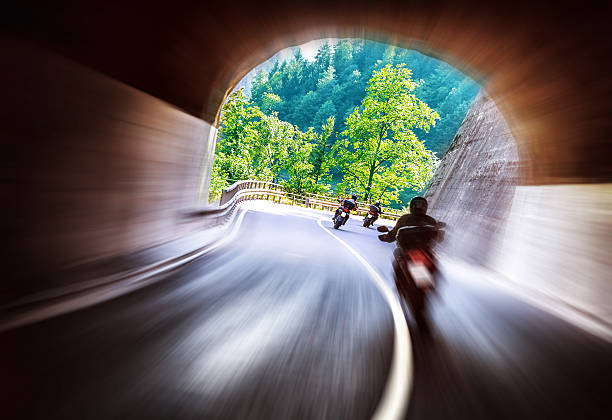 Group of bikers touring along European mountains, riding in tunnel, extreme lifestyle, slow motion, traveling and tourism concept