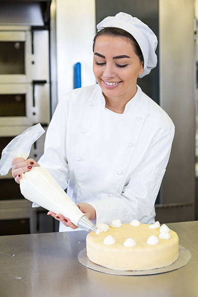 istock Baker prepares cake in bakehouse with whipped cream 475332739