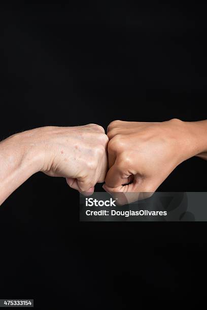 Fistbump Over Black Background Stock Photo - Download Image Now - Fist Bump, Black Background, 2015